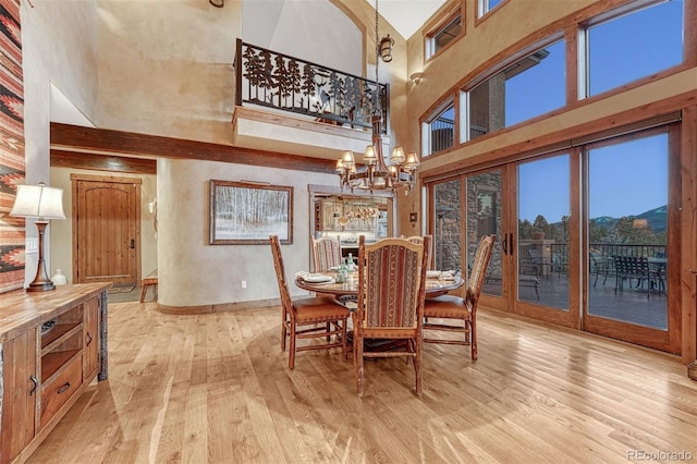 dining area featuring a high ceiling, light wood-type flooring, and an inviting chandelier