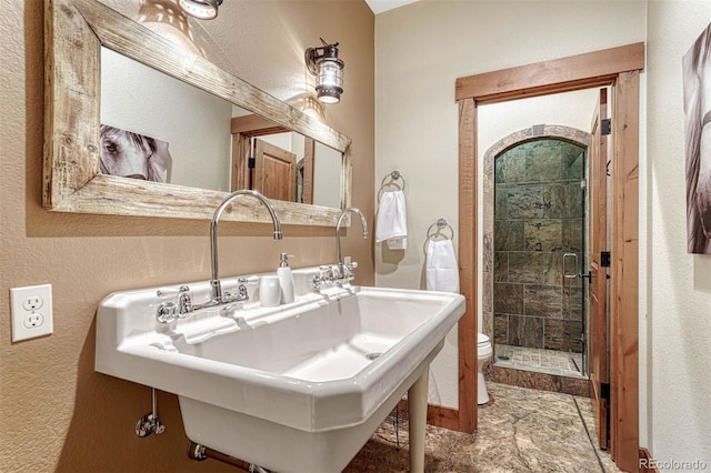 bathroom with an enclosed shower, sink, and toilet