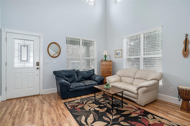 living room with a towering ceiling and light wood-type flooring