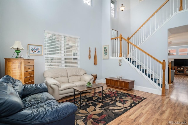 living room with a towering ceiling, wood-type flooring, and plenty of natural light