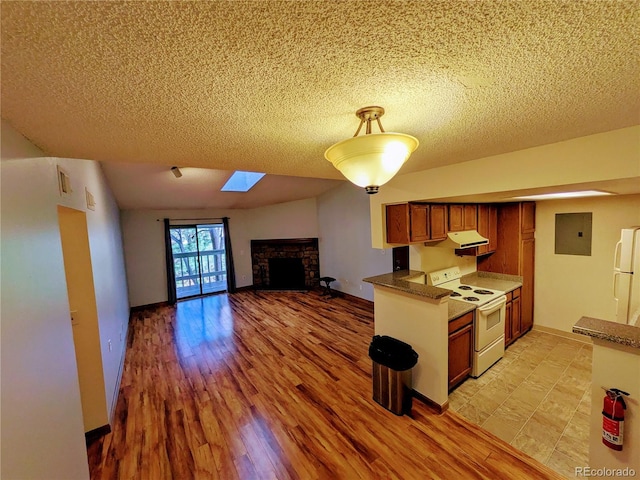 kitchen with white appliances, brown cabinets, a textured ceiling, and a stone fireplace