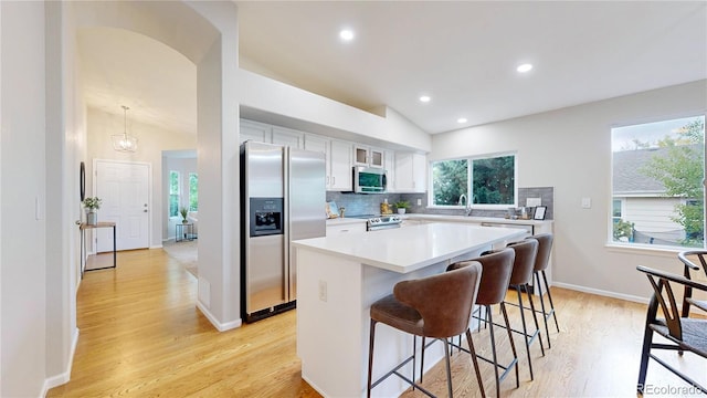 1229 Berganot Trl, Castle Pines, CO 80108 - kitchen featuring stainless steel appliances, a kitchen breakfast bar, white cabinetry, a center island, and light wood finished floors