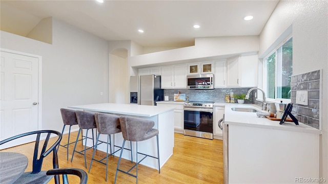 1229 Berganot Trl, Castle Pines, CO 80108 - kitchen featuring appliances with stainless steel finishes, a sink, a kitchen bar, light wood-type flooring, and a center island