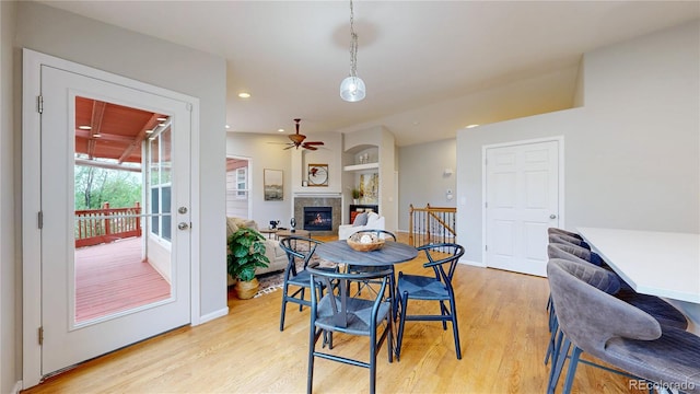 1229 Berganot Trl, Castle Pines, CO 80108 - dining room featuring light wood finished floors, a glass covered fireplace, ceiling fan, baseboards, and recessed lighting