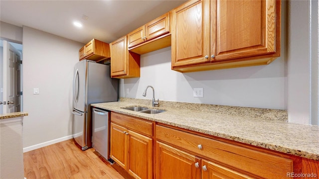 1229 Berganot Trl, Castle Pines, CO 80108 - kitchen featuring a sink, dishwasher, light wood finished floors, and light stone counters