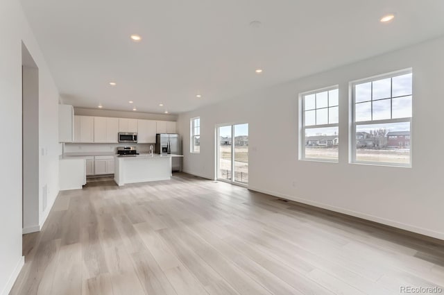 unfurnished living room featuring baseboards, visible vents, light wood-style flooring, and recessed lighting