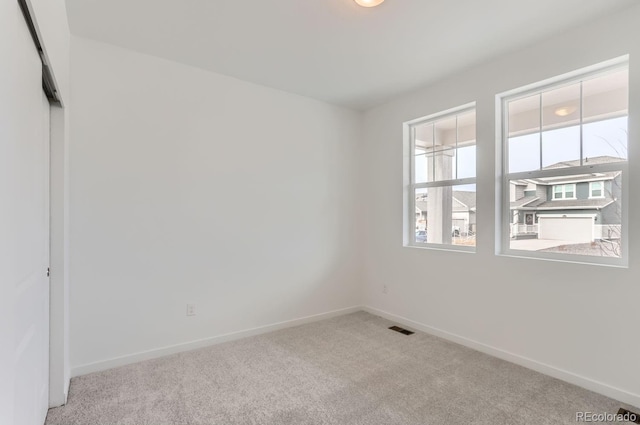 empty room with carpet floors, visible vents, and baseboards