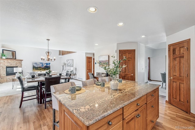 942 Xenon Ct, Golden, CO 80401 - kitchen featuring open floor plan, light wood finished floors, light stone counters, a glass covered fireplace, and recessed lighting