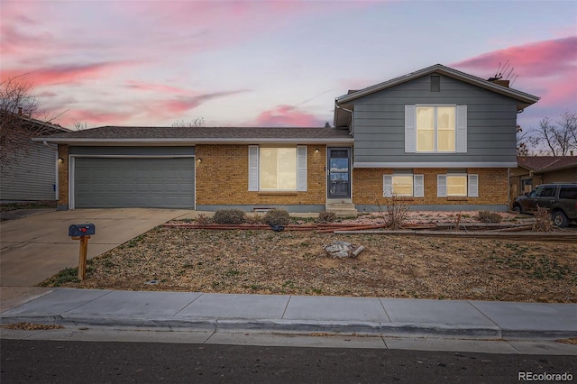 tri-level home featuring brick siding, driveway, and an attached garage