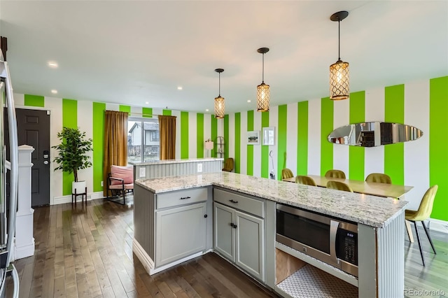 kitchen featuring dark wood-type flooring, gray cabinets, stainless steel microwave, decorative light fixtures, and wallpapered walls