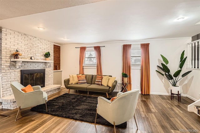 living room with ornamental molding, baseboards, wood finished floors, and a fireplace