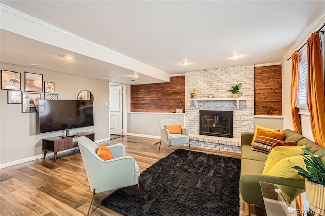 living area with wood walls, a brick fireplace, baseboards, and wood finished floors