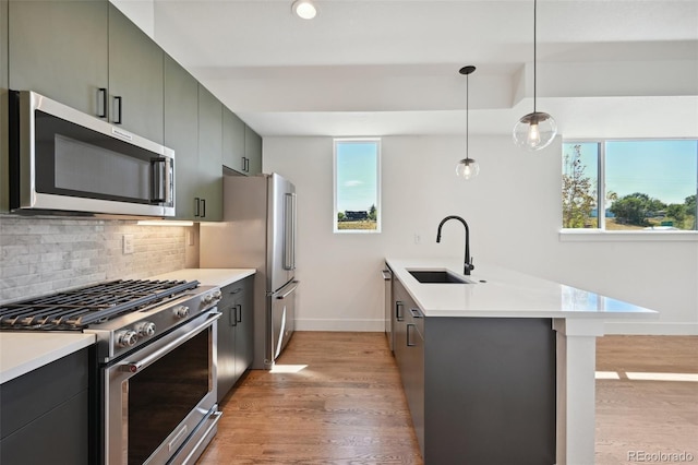 kitchen featuring tasteful backsplash, a wealth of natural light, appliances with stainless steel finishes, a peninsula, and a sink