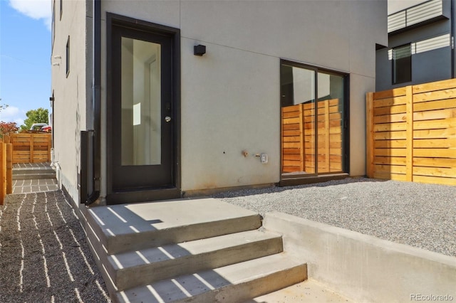 property entrance with stucco siding and fence