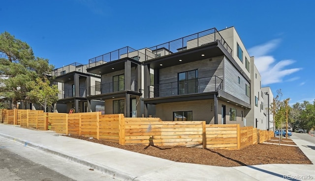 modern home featuring a balcony and a fenced front yard