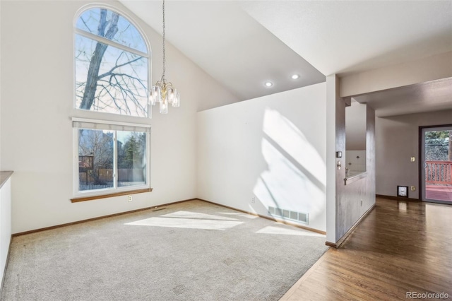 unfurnished living room featuring a notable chandelier, visible vents, wood finished floors, high vaulted ceiling, and baseboards