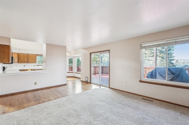 living room featuring light carpet, light wood finished floors, baseboards, and visible vents