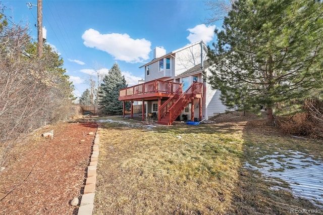 rear view of property with a yard, a chimney, fence, a wooden deck, and stairs