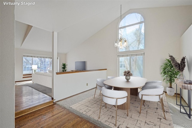 dining area with high vaulted ceiling, baseboards, a chandelier, and wood finished floors