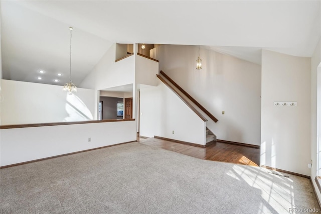 unfurnished living room featuring high vaulted ceiling, carpet flooring, baseboards, and stairs