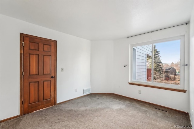 spare room featuring carpet, visible vents, and baseboards