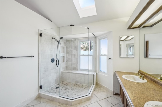 full bath featuring a stall shower, vaulted ceiling with skylight, baseboards, tile patterned floors, and vanity