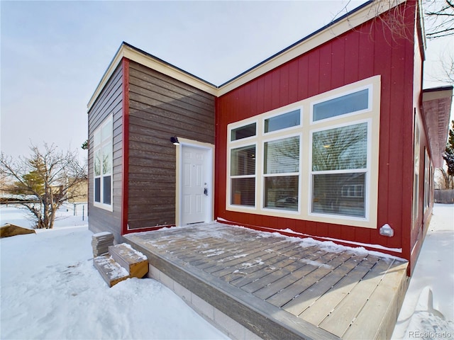 snow covered property entrance with a deck