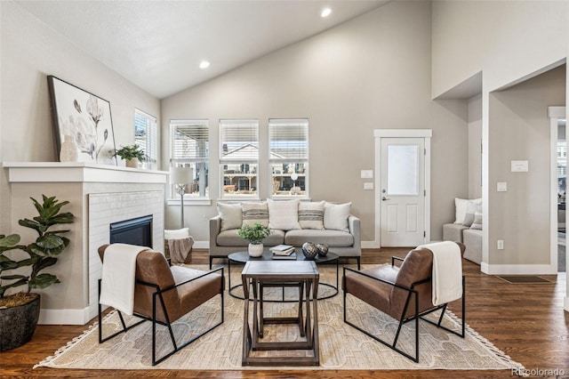 living room featuring a fireplace, wood-type flooring, and high vaulted ceiling