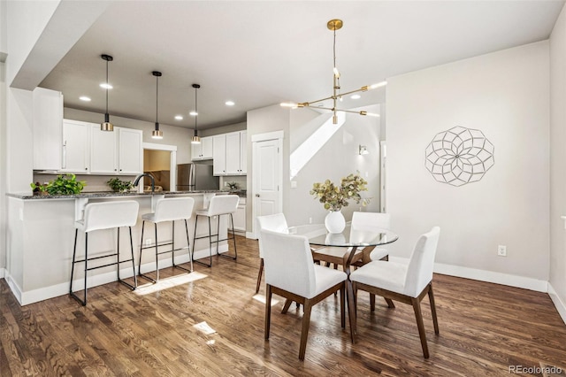 dining area with sink, dark wood-type flooring, and a chandelier