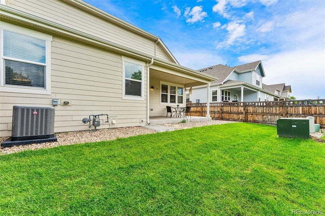 rear view of property with central AC unit, a patio area, and a lawn