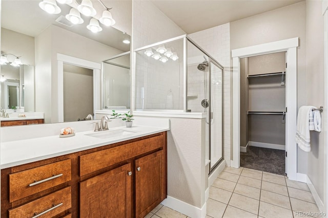 bathroom with a shower with door, vanity, and tile patterned floors