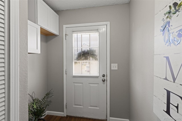 doorway to outside with a textured ceiling, a wealth of natural light, and dark wood-type flooring