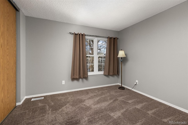 carpeted empty room featuring a textured ceiling