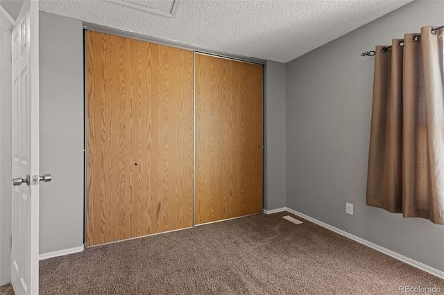 unfurnished bedroom featuring carpet, a textured ceiling, and a closet