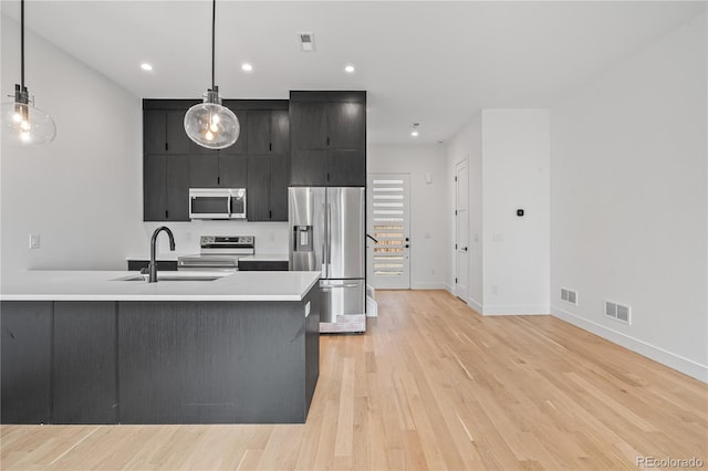 kitchen with visible vents, hanging light fixtures, stainless steel appliances, light countertops, and a sink