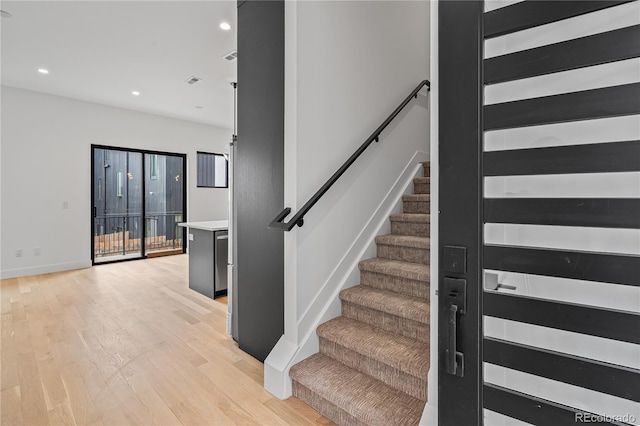 staircase featuring baseboards, wood finished floors, and recessed lighting