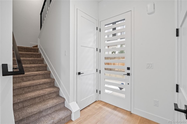 entryway featuring light wood-style floors, baseboards, and stairway