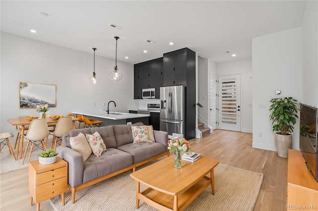 living room with light wood-style floors, stairway, visible vents, and recessed lighting