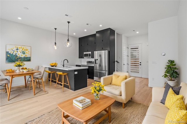 living room with baseboards, recessed lighting, visible vents, and light wood-style floors