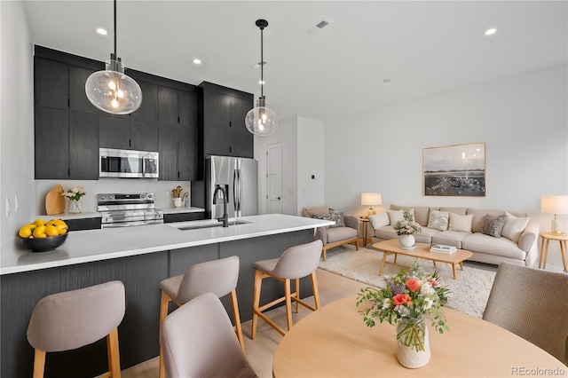 kitchen featuring modern cabinets, open floor plan, decorative light fixtures, stainless steel appliances, and light countertops