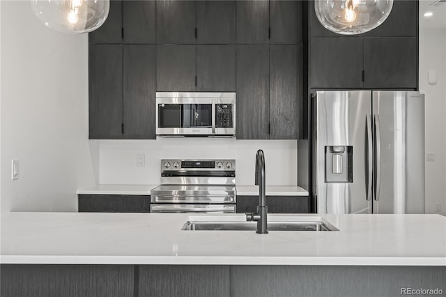 kitchen featuring hanging light fixtures, modern cabinets, stainless steel appliances, and light countertops