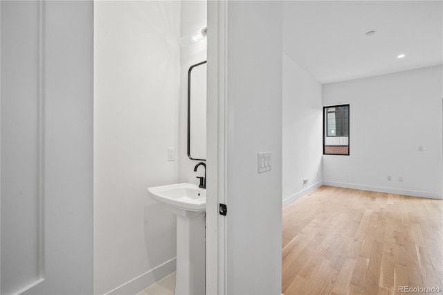 bathroom with a sink, baseboards, wood finished floors, and recessed lighting