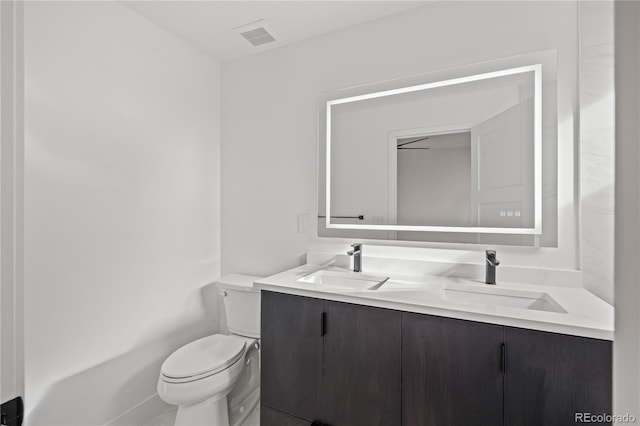 bathroom with toilet, visible vents, and vanity