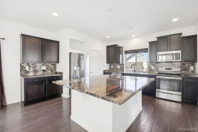 kitchen featuring backsplash, dark hardwood / wood-style flooring, a kitchen island, and appliances with stainless steel finishes