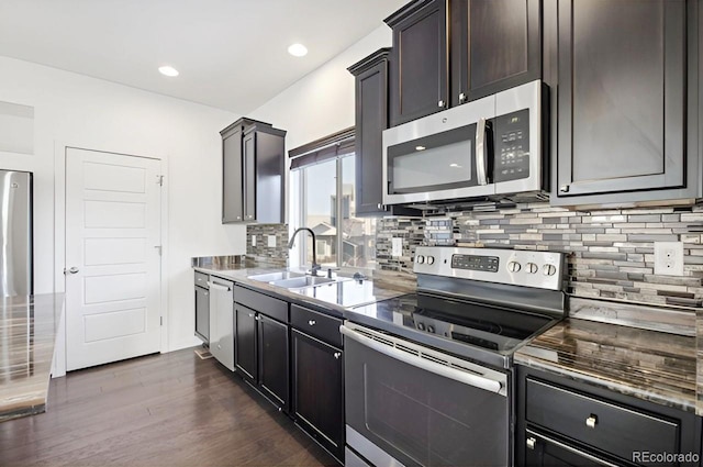 kitchen featuring dark brown cabinetry, sink, stainless steel appliances, tasteful backsplash, and dark hardwood / wood-style flooring