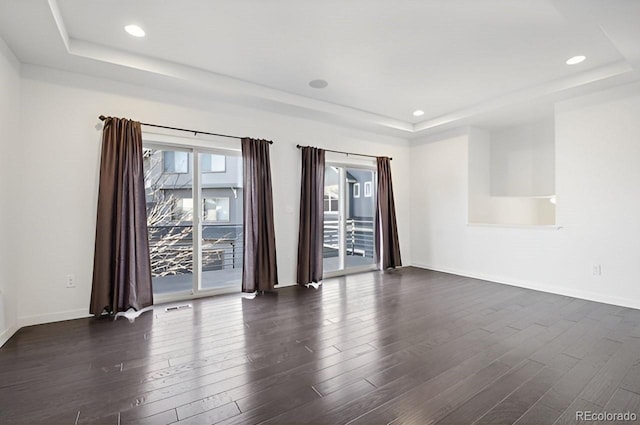 unfurnished room featuring dark hardwood / wood-style floors and a tray ceiling