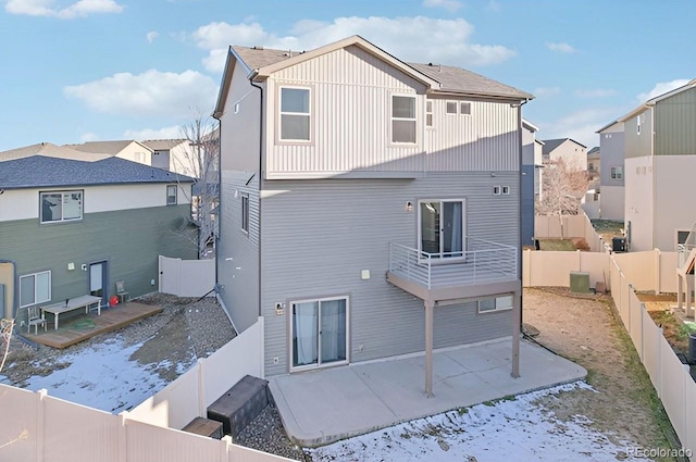 snow covered rear of property featuring a balcony and central air condition unit