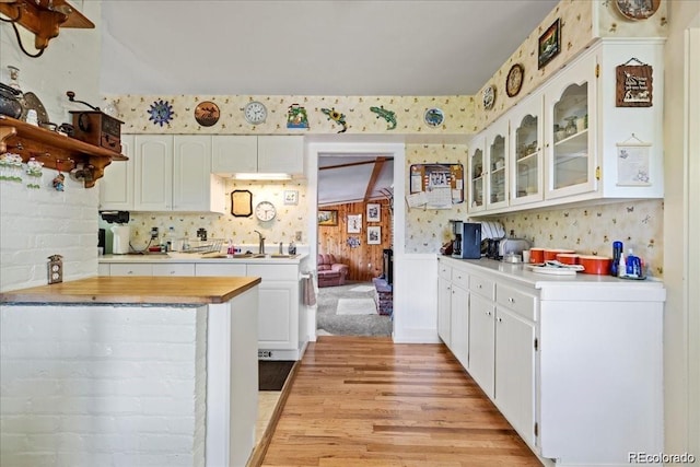 7750 W 5th Ave, Lakewood, CO 80226 - kitchen with light wood finished floors, glass insert cabinets, a sink, white cabinets, and open shelves