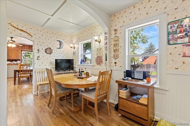 7750 W 5th Ave, Lakewood, CO 80226 - dining space featuring wallpapered walls, arched walkways, wood finished floors, wainscoting, and a ceiling fan