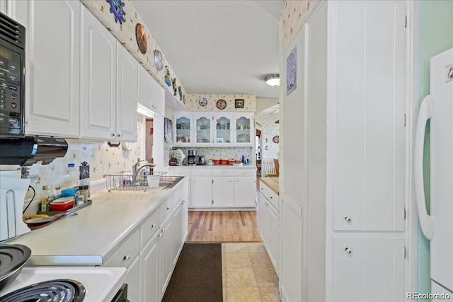 7750 W 5th Ave, Lakewood, CO 80226 - kitchen with light countertops, white cabinetry, a sink, glass insert cabinets, and freestanding refrigerator